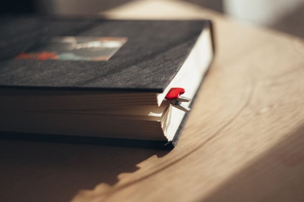 A closed book with a red ribbon bookmark